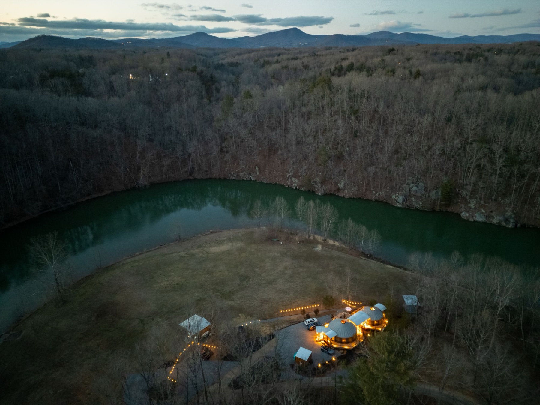 Aerial view at dusk of a lakefront vacation rental with the Blue Ridge Mountains in the distance